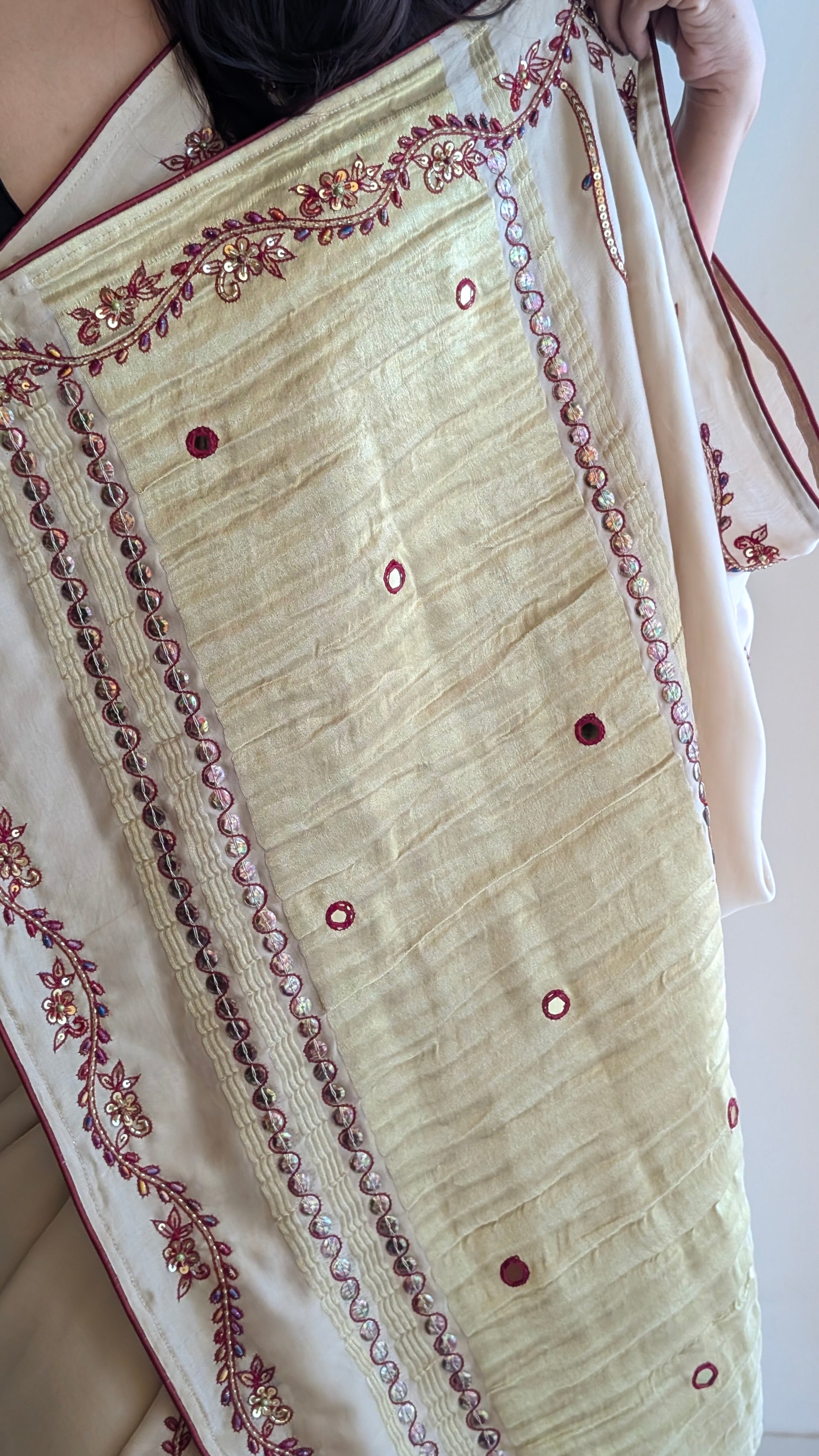 Close-up of a cream-colored modal silk saree with intricate red embroidery 