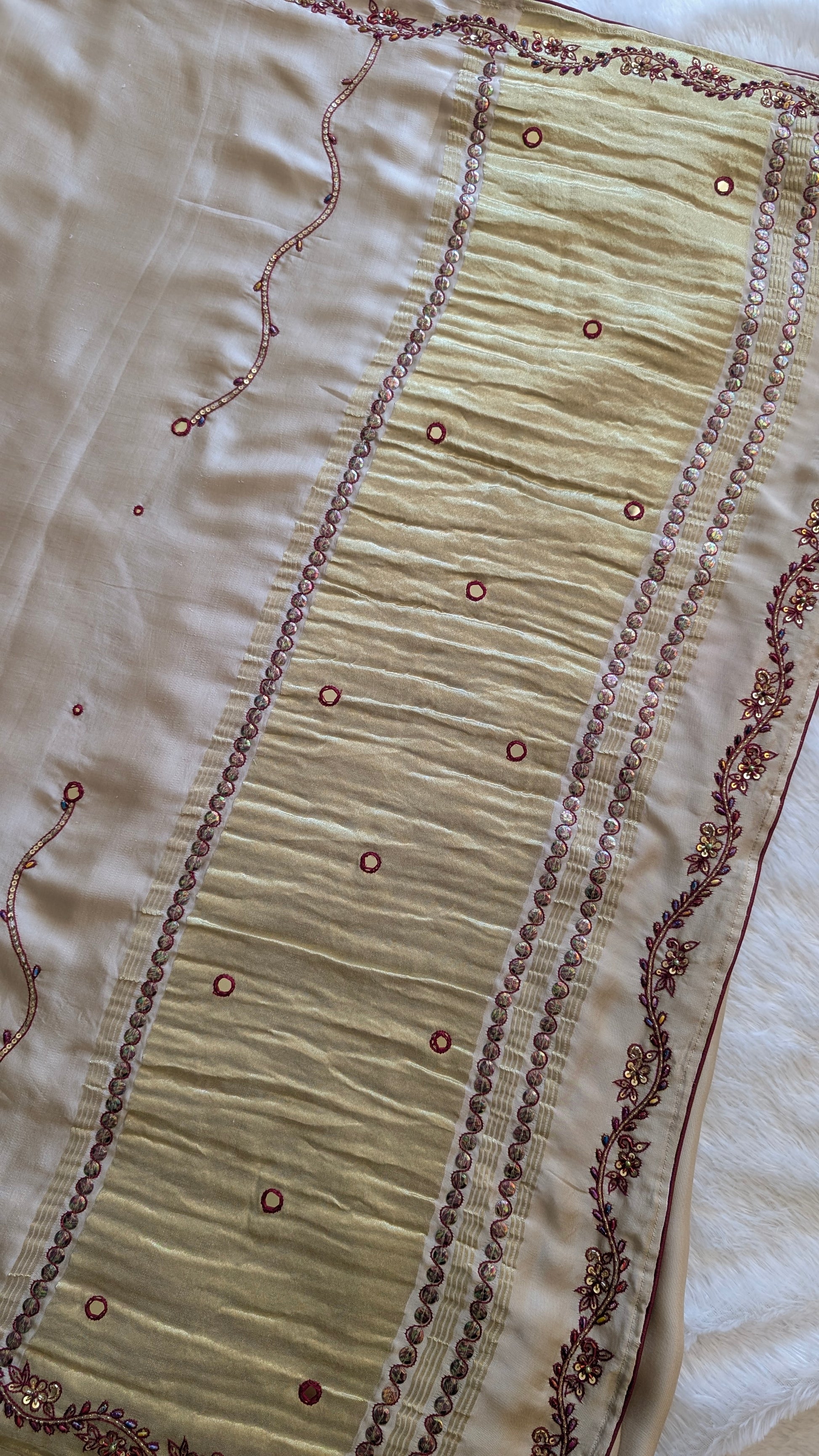 Close-up of a cream-colored modal silk saree with intricate red embroidery 